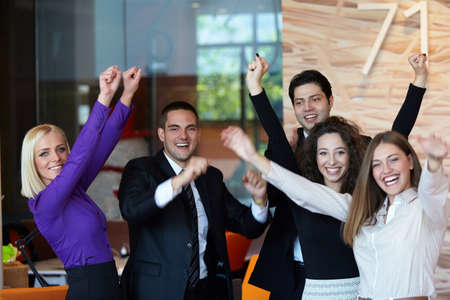 Business team celebrating a triumph in office with arms upの写真素材