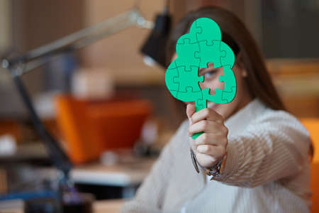 business woman with tree puzzle looking happy and smilingの写真素材