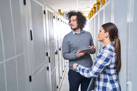 two young technicians working at a data center on server maintenance