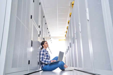 female technician working on server maintenance in white server room