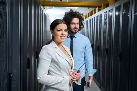Young couple working at a data center. Black server room.