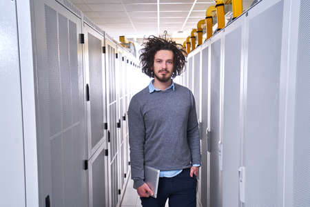 Young technician working in white server room