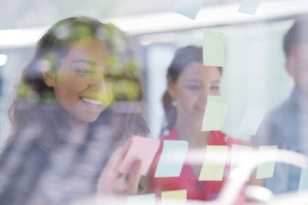business, startup, planning, management and people concept - happy creative team writing on stickers...