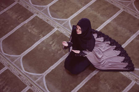 Young muslim woman praying in mosque