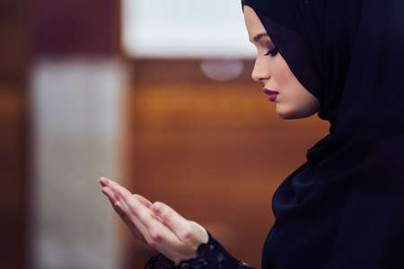 Young muslim woman praying in mosque