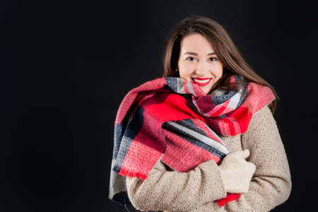 Pretty girl in warm winter clothes, isolated, on black backgroundの写真素材