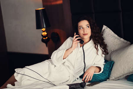 Girl talking on the phone in the hotel roomの写真素材