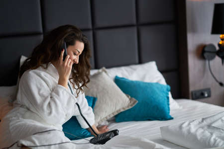 Girl talking on the phone in the hotel roomの写真素材