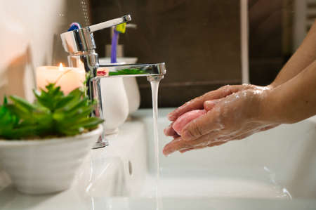 Washing hands with soap and hot water at home bathroom sink women cleansing hand hygiene for...
