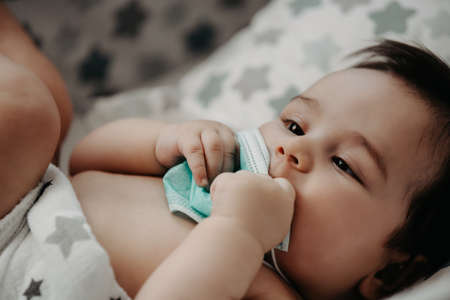 Sick baby with a mask on his face laying in his bed. Mother Checks The Temperature Of A Sick Baby.の写真素材