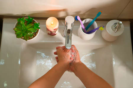 Washing hands with soap and hot water at home bathroom sink women cleansing hand hygiene for coronavirus outbreak prevention. Corona Virus pandemic protection by washing hands frequently.の写真素材