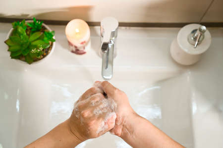 Washing hands with soap and hot water at home bathroom sink women cleansing hand hygiene for coronavirus outbreak prevention. Corona Virus pandemic protection by washing hands frequently.の写真素材