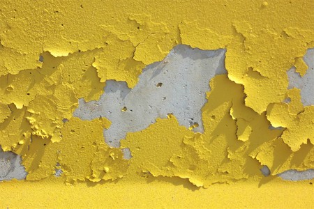 Detached sheets of aged reflective paint applied on concreteの写真素材
