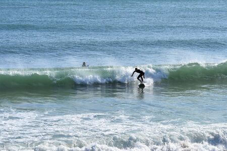Surfer riding a wave disheveled by the wind in a winter seaの写真素材