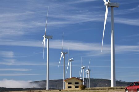 Row of wind power generators located next to a shelter in highland over the clouds