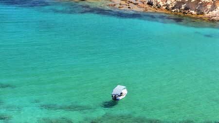 Aerial view of a small boat floating in the transparent emerald sea of Menorcaの写真素材