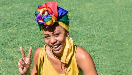 Closeup of a young african origin woman, wearing a headdress made with the rainbow flag rolled up...