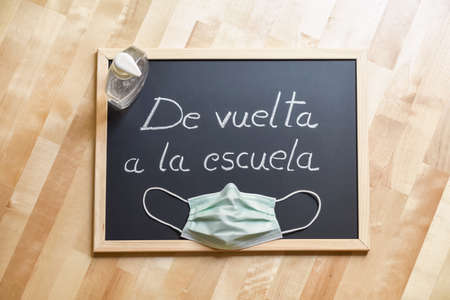 Blackboard with handwritten label "back to school", facial mask and dispenser of hydroalcoholic gel. Protective elements for returning to classrooms.の写真素材