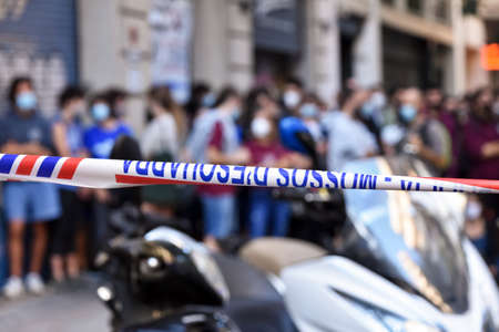 Barcelona / Spain, 2020-09-22 Neighborhood protest against the eviction of a house for non-payment of rent. Foreground of a plastic tape placed as police barrier with a blurry protesters view behind.のeditorial素材