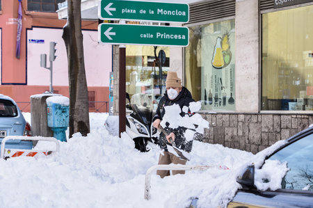 Madrid / Spain, 2021-01-10 Historic snowfall in Madrid. A man shovels snow to clear the sidewalk on a city center street after the heavy snowfall.のeditorial素材