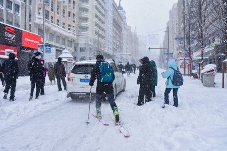 Madrid / Spain, 2021-01-09 Historic snowfall in Madrid. A car tries to travel along the "Gran VÃ­a" street during the "Filomena" snowstorm followed by a skier.のeditorial素材