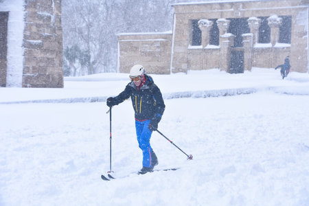 Madrid / Spain, 2021-01-09 Historic snowfall in Madrid. A man moving on skis under the "Filomena" snowstorm passes in front of the egyptian "Debod" temple in the west park.のeditorial素材