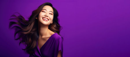 Portrait of a beautiful young Asian woman smiling on a purple background with flowing long shiny wavy hair.の素材