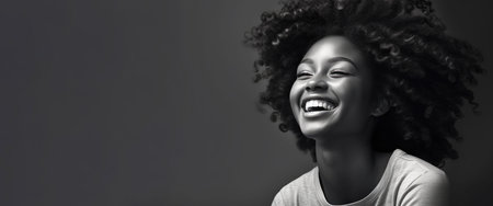 Very beautiful dark-skinned American girl with curly hair smiling on gray background.の素材