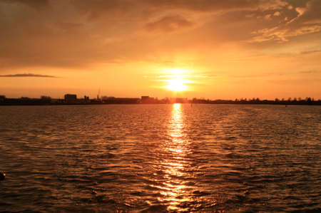 Sunset over a Dutch canal near Sneek. Dramatic clouds and the light reflected in the water of the setting sun.の写真素材