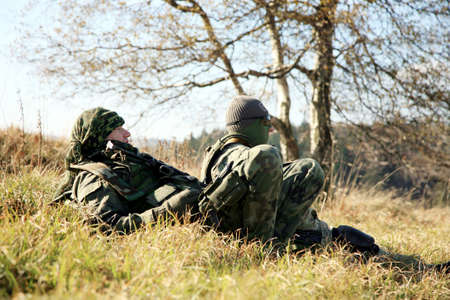 Armed soldier in camouflage is resting after the patrol.の写真素材