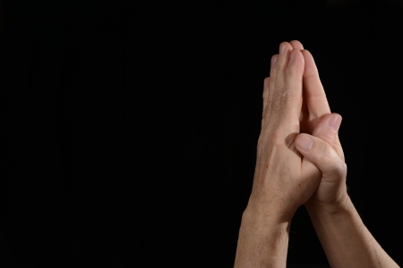 Praying hands on black background with room on left for artworkの写真素材