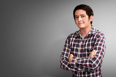 Portrait of young man standing against grey background