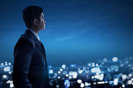 Asian business man looking at night cityの写真素材