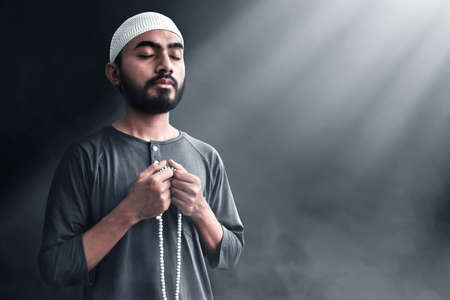 Religious muslim man praying with rosary beadsの写真素材