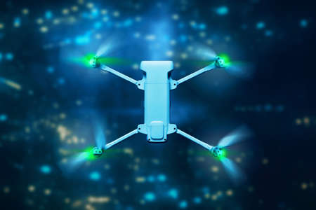 Drone quadcopter flying above city at night