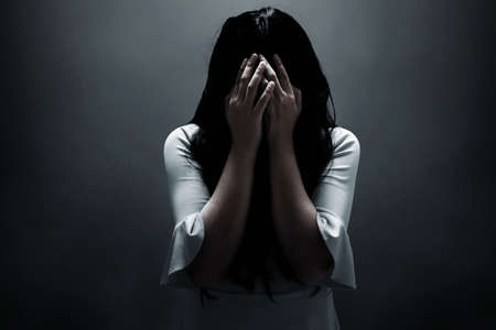 Scared woman on dark backgroundの写真素材