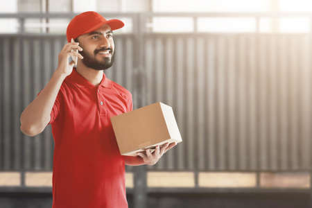 Smiling delivery man holding cardboard boxの写真素材