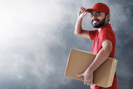Smiling delivery man holding cardboard boxの写真素材