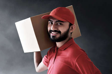 Smiling delivery man holding cardboard boxの写真素材