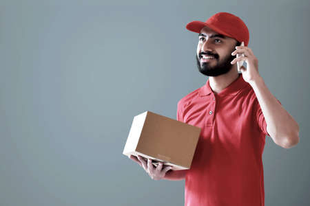 Smiling delivery man holding cardboard boxの写真素材