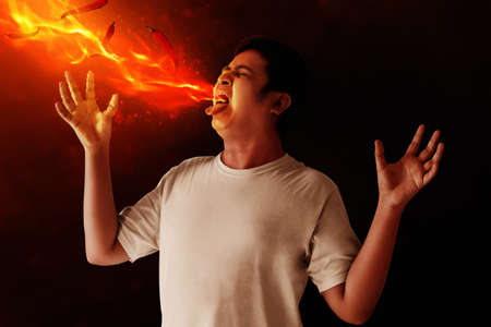 Portrait of young man eating chili pepperの写真素材