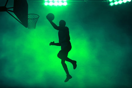 3d illustration shadow silhouette of professional basketball player layup on dark green smoke backgroundの写真素材