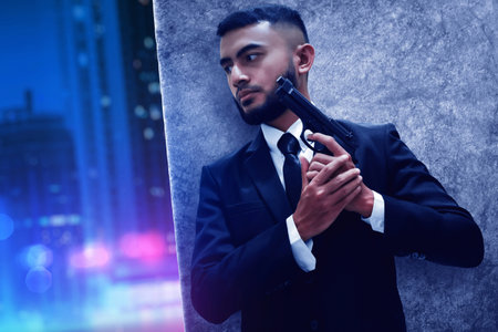 Beard man in black suit with gun hiding behind dark grunge wall on the street at night city