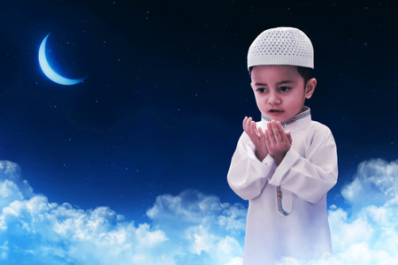 Portrait of asian muslim kid praying at night sky with stars and crescent moon, eid adha mubarak conceptの写真素材