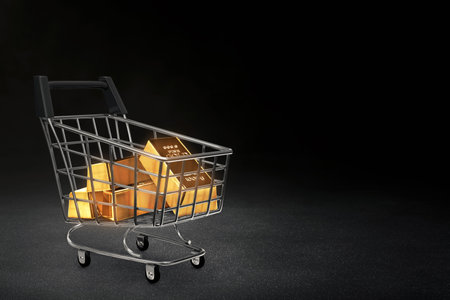Stack of shiny gold bars in shopping cart  isolated on dark backgroundの写真素材