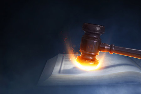 Hammer hitting book page with fire burning effect on dark smoke backgroundの写真素材