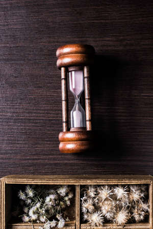 Hourglass and flower box on table background.