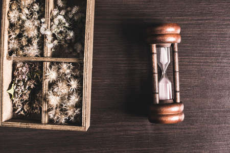Hourglass and flower box on table background.
