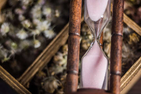 Hourglass on flower box on table background.