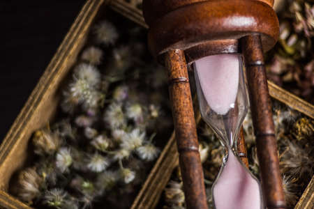 Hourglass on flower box on table background.